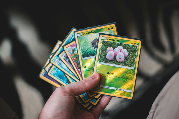Hand holding a collection of Pok&eacute;mon cards, highlighting the husband's valued Pok&eacute;mon card collection controversy.