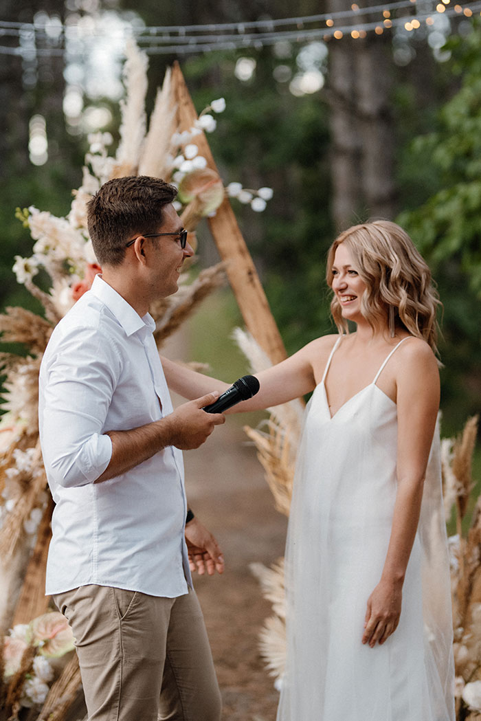 Woman staging her apartment to impress a guy smiling with groom during outdoor wedding ceremony.