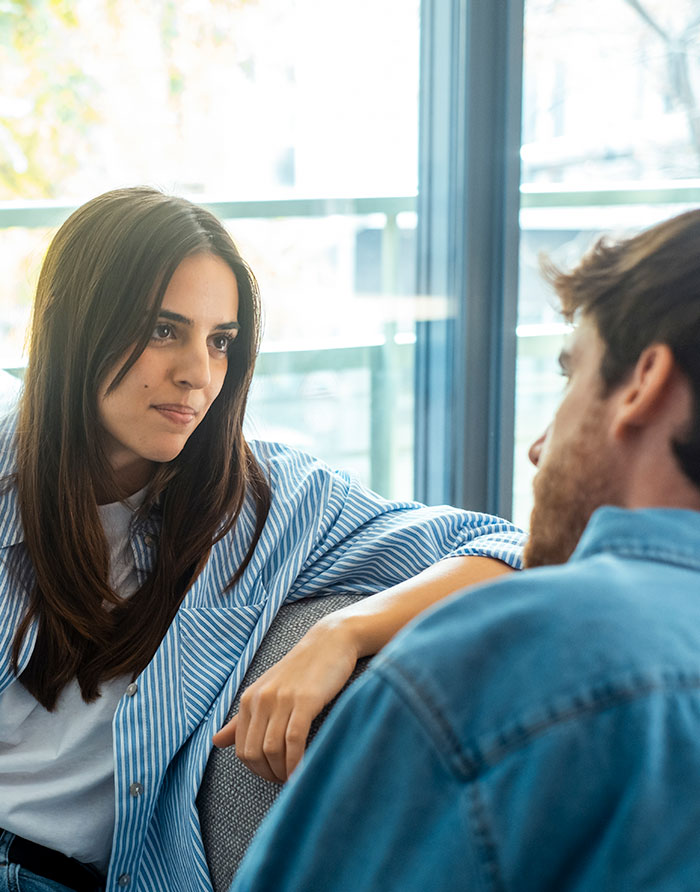 Woman staging her apartment to impress a guy, having a heartfelt conversation in a bright living room setting.