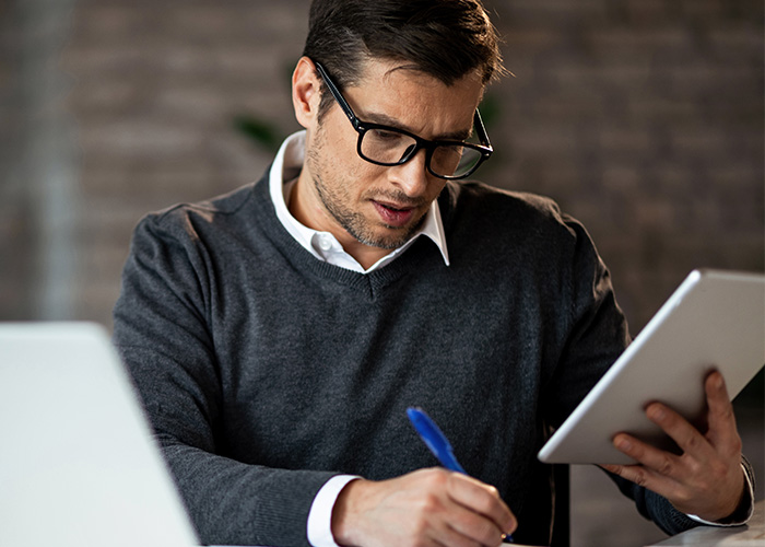 Man accountant wearing glasses, working with tablet and pen, focused on accounting tasks in a modern office setting