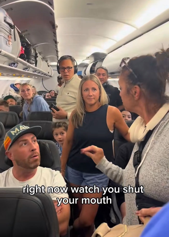 Woman causing disturbance on plane as passengers react nervously during heated encounter on flight interior. Woman causing disturbance on plane as passengers react nervously during heated encounter on flight interior.