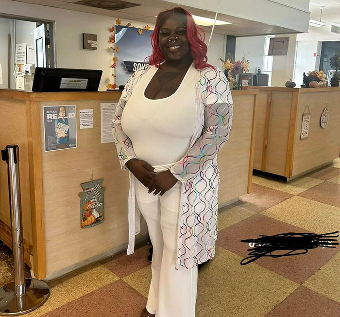 Woman standing inside a pet store, smiling, dressed in white, related to incident involving argument outside pet store.