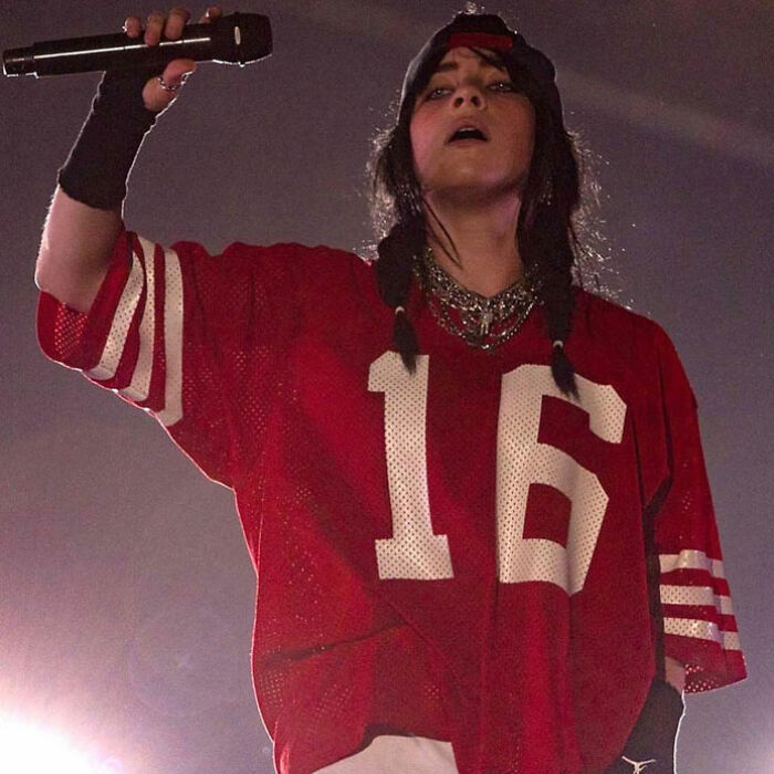 Billie Eilish performing at Miami concert while fans react to man trying to snatch her on stage.