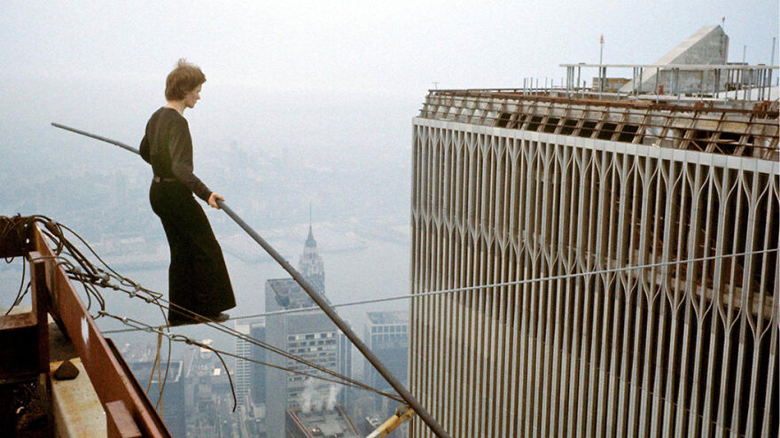 Tightrope walker balancing on a wire between skyscrapers in a daring scene from movies based on true stories.