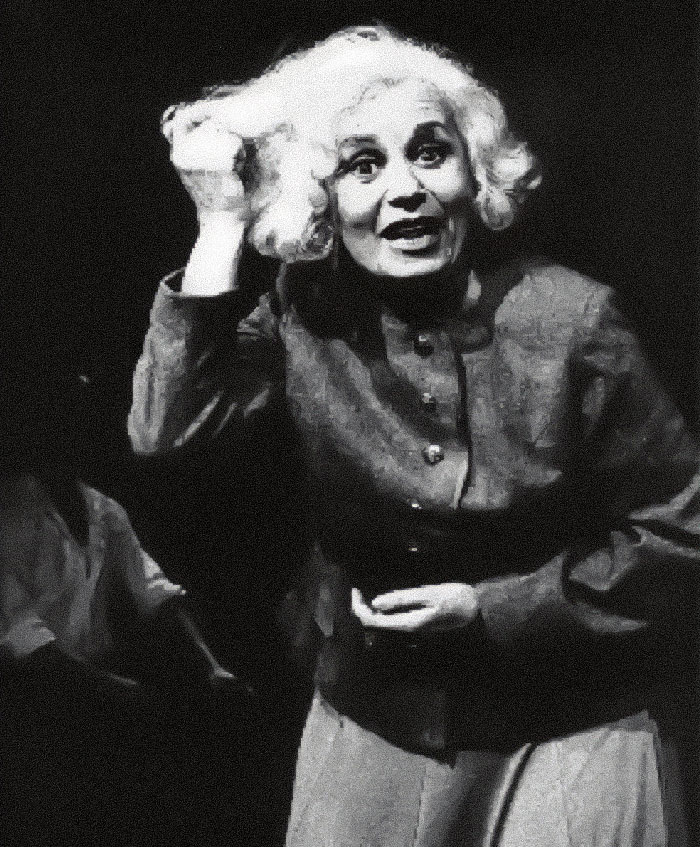Holocaust survivor Ruth Posner speaking passionately in a black and white photo during a dramatic performance.