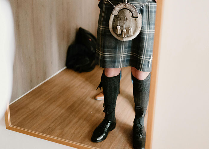 Person wearing traditional Scottish kilt and sporran standing in front of a mirror, illustrating loopholes against horrible bosses.
