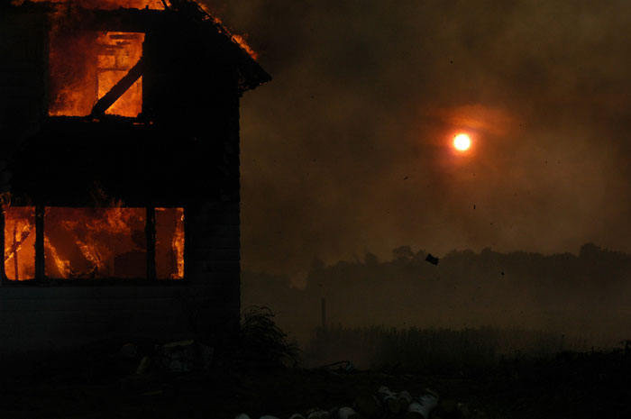 House on fire at night with bright flames visible, illustrating some of the worst crimes shared from hometowns.
