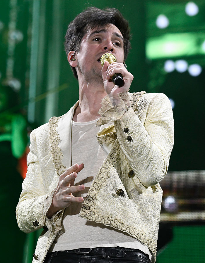 Male singer performing on stage with microphone, wearing a decorative jacket, highlighting Mormon Backflip Theory trend.