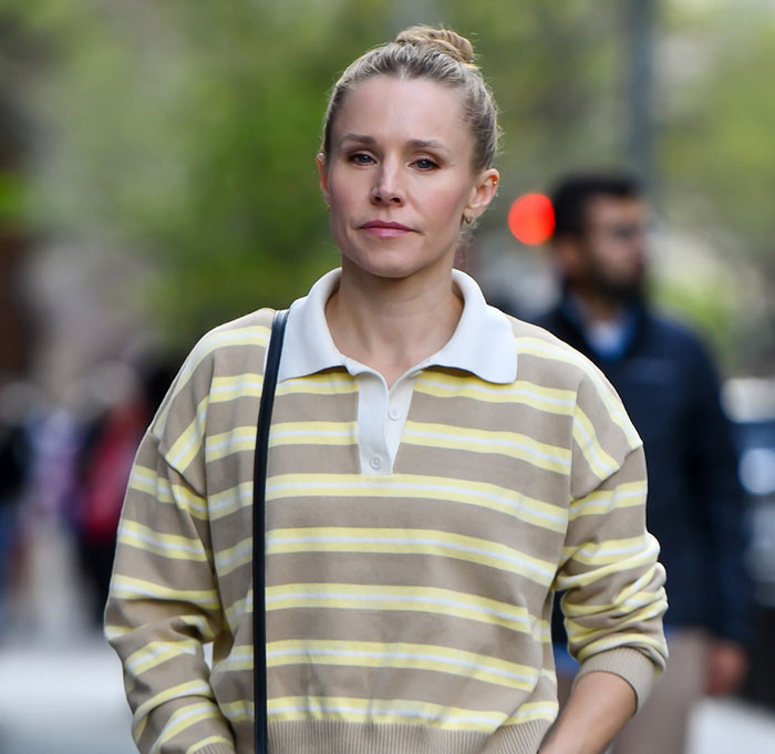 Kristen Bell wearing a striped shirt, walking outdoors amid experts condemning triggering post and backlash.