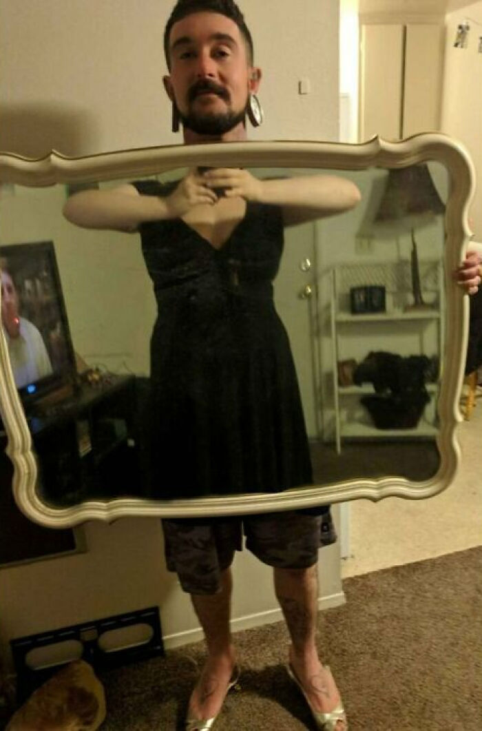 Person holding a mirror showing a reflection of them wearing a black dress, highlighting funny mirror selling fails.
