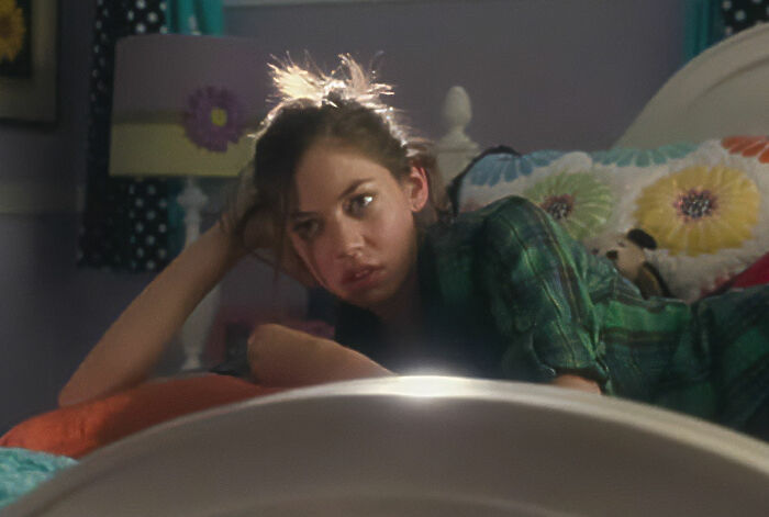 Young woman in casual clothes lying on bed, looking tired and frustrated, depicting unrealistic women movie tropes.