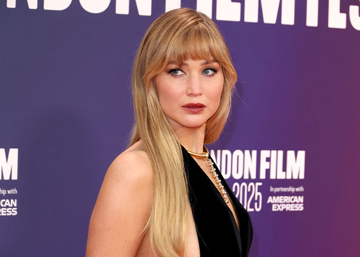Jennifer Lawrence at a film event, posing in a black dress, addressing plastic surgery plans after viral video reaction.
