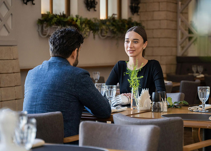 A woman and a man having a conversation at a restaurant, illustrating creepy things women said or did to men.