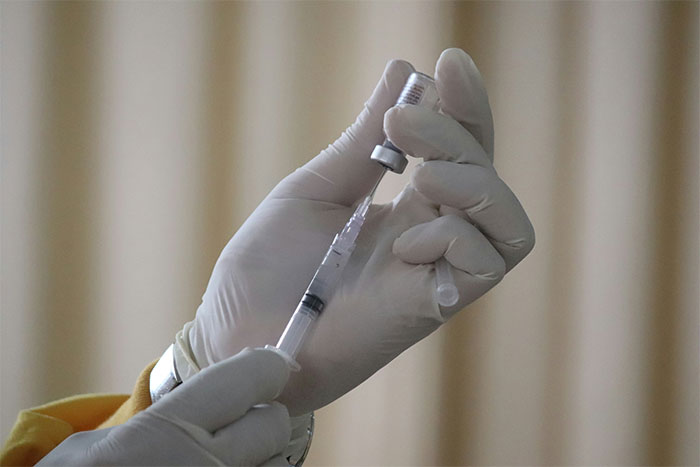 Close-up of gloved hands preparing a vaccine injection highlighting concerns about unvaccinated kids and child safety debates.