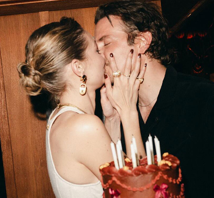 A couple sharing a kiss at a party, with a cake in the foreground, discussed by plastic surgeons about a new look. A couple sharing a kiss at a party, with a cake in the foreground, discussed by plastic surgeons about a new look.