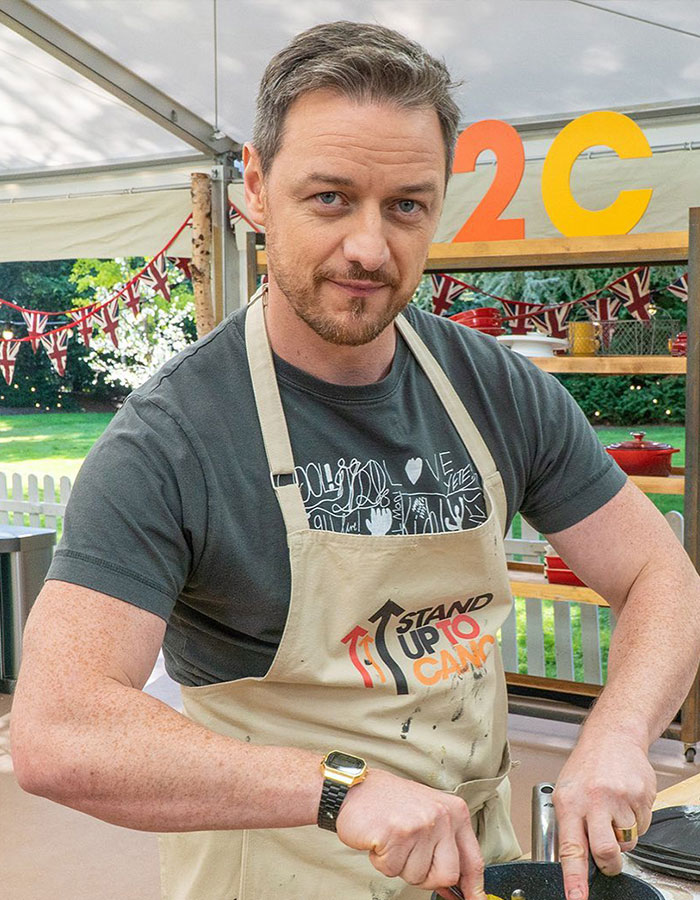 Actor wearing a Stand Up To Cancer apron preparing food, featured in a list of famous men shorter than fans imagined.