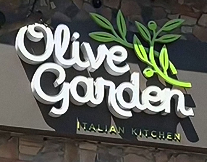 Olive Garden sign with olive branch logo at Italian kitchen restaurant, related to American tourist request in Italy.