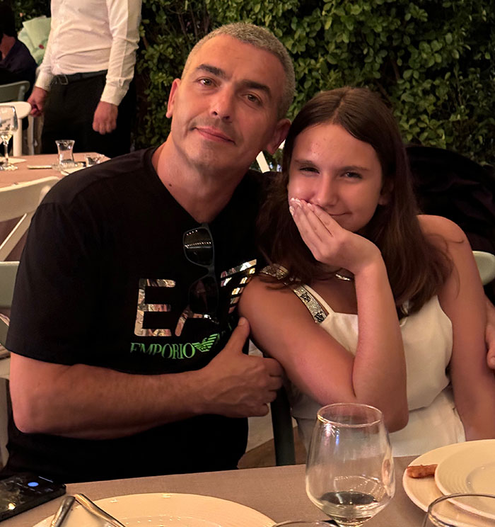 Man and young girl at a dinner table, with some blaming the parents in a 12-year-old subway surfing tragedy.