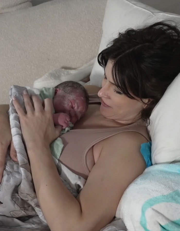 Woman holding newborn baby after giving birth, highlighting birth on Twitch livestream and public reactions.