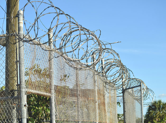 Barbed wire fence under blue sky symbolizing confinement related to 12-year-old escaping severe mistreatment at home.
