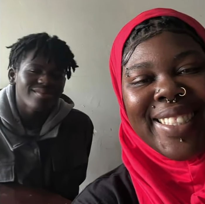 Two people smiling indoors, with focus on woman wearing a red headscarf related to woman loses life pet store incident.