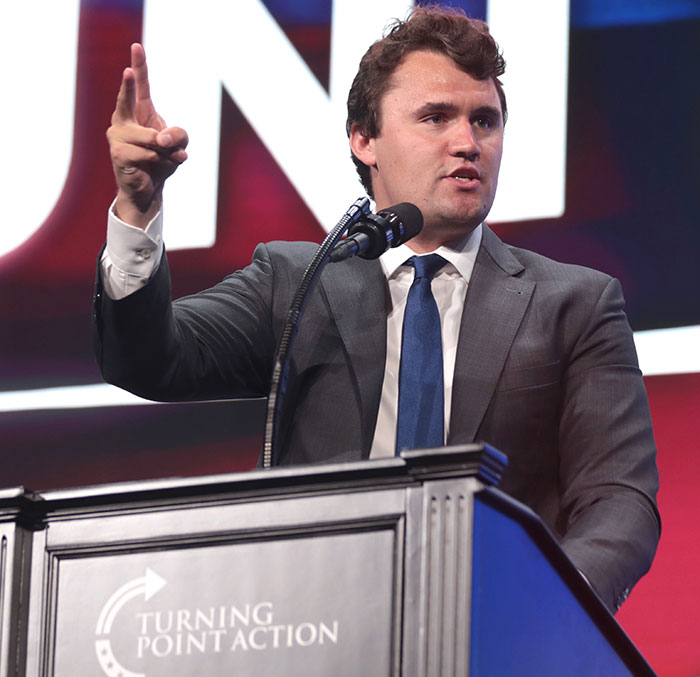 Man speaking at a podium with Turning Point Action logo, related to dad discovering Charlie Kirk homework assignment outrage.