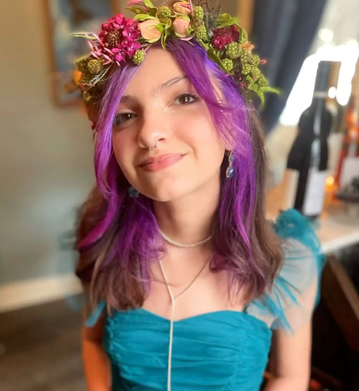 Teen girl with purple hair and floral crown smiling indoors, highlighting controversy over pelvic tattoo at 16 years old. Teen girl with purple hair and floral crown smiling indoors, highlighting controversy over pelvic tattoo at 16 years old.