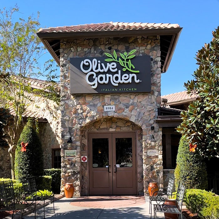 Olive Garden restaurant exterior with stone facade and clear blue sky, related to Olive Garden hoax involving student incident. Olive Garden restaurant exterior with stone facade and clear blue sky, related to Olive Garden hoax involving student incident.