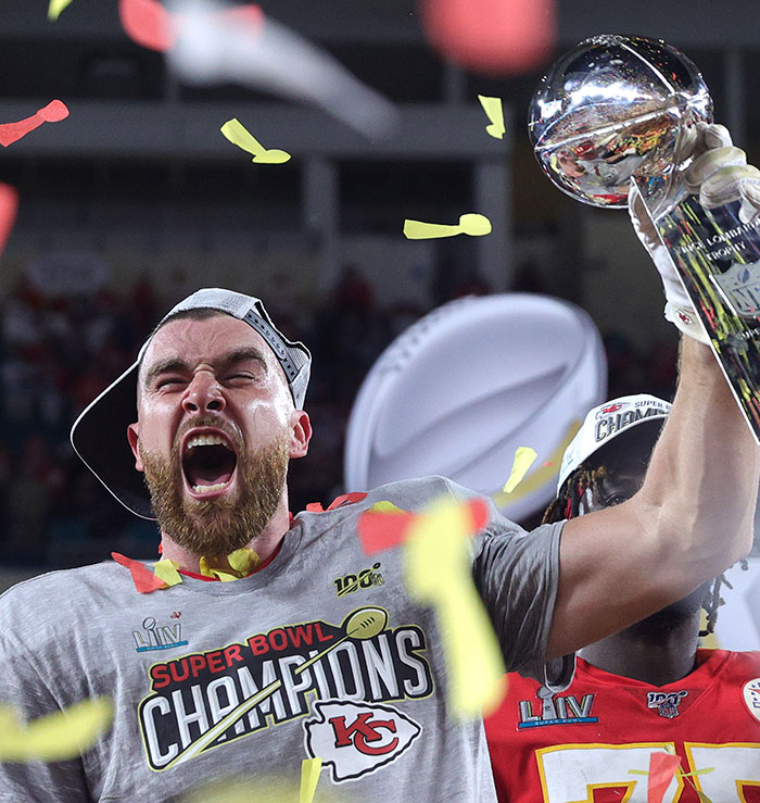 Travis Kelce celebrating Super Bowl victory holding trophy with confetti, linked to Taylor Swift fans and tradwife controversy.