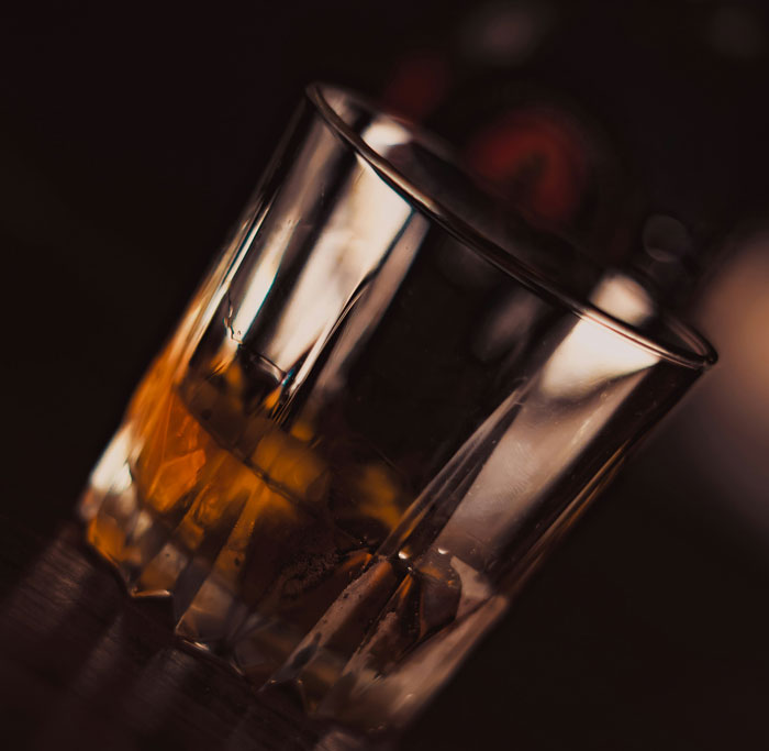 A close-up of a glass with amber liquid, symbolizing a moment reflecting on horrifyingly cruel people met.