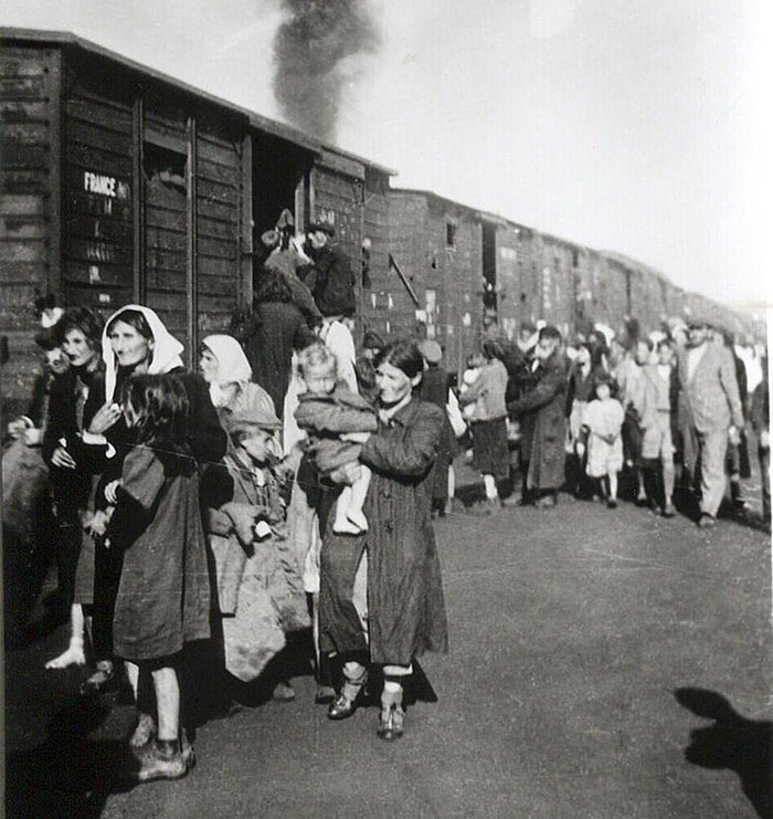 Holocaust survivors and families waiting beside a train during World War II, related to Ruth Posner and husband story.