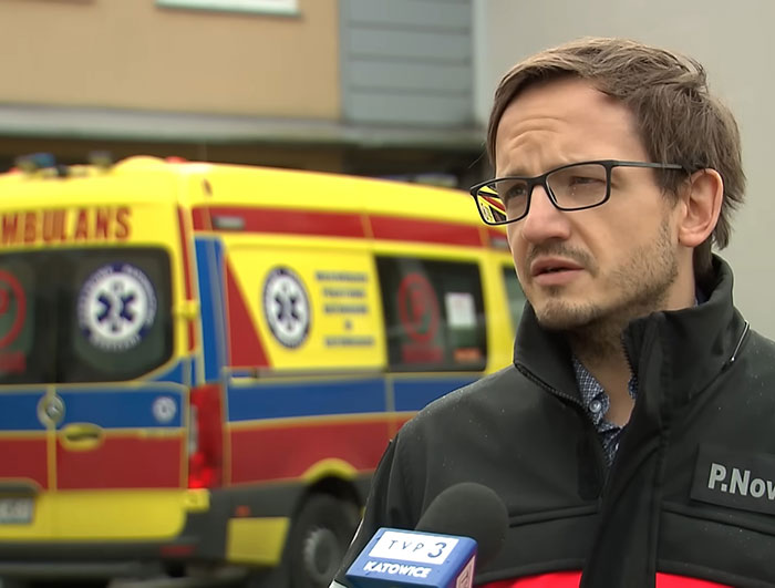 Man wearing glasses and black jacket giving interview near ambulance about woman missing for 27 years found emaciated