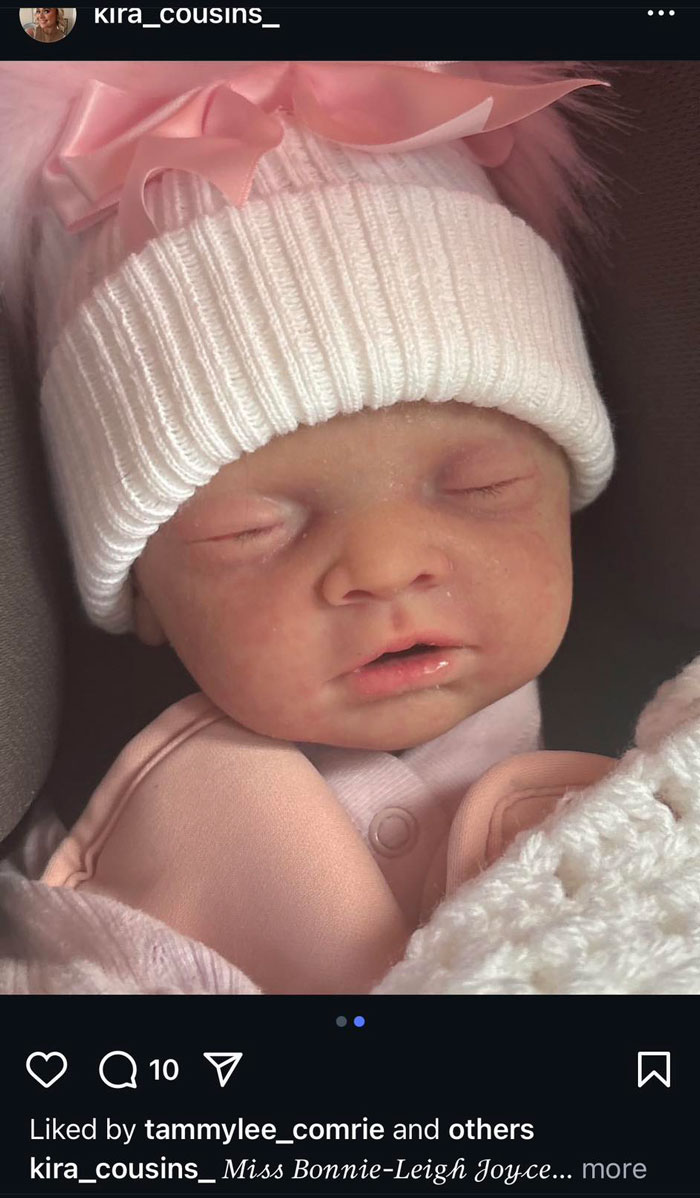 Realistic baby doll wearing a white hat with pink bow, highlighting woman's 10-month lie involving baby doll discovery.