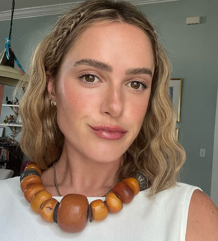 Woman with wavy blonde hair wearing a chunky beaded necklace, related to David Harbour&rsquo;s friend clapping back at accusations.