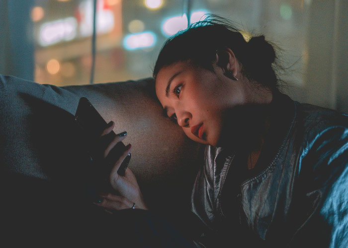 Young woman looking worried and focused on her phone at night, illustrating creepy things women said or did to men.