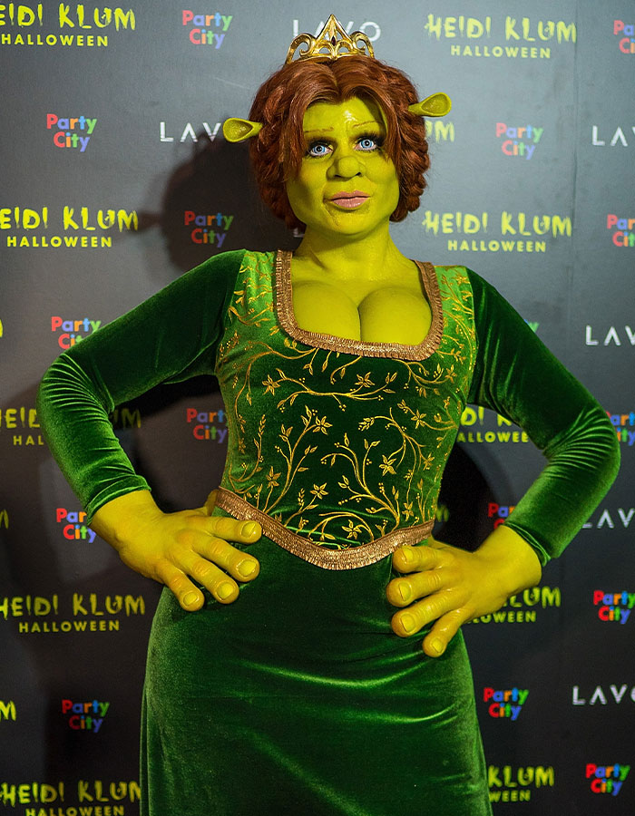 Heidi Klum in a detailed green costume with face makeup and prosthetic ears at a Halloween event.