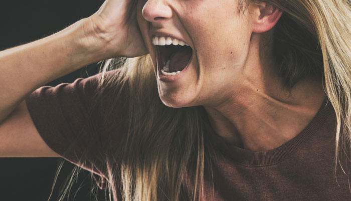 Woman shouting angrily with hand near ear, expressing frustration over on-site landlord rent increase dispute.