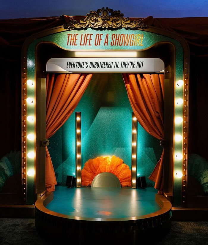 Small illuminated stage with orange curtains and sign reading The Life Of A Showgirl, relating to Taylor Swift leaked lyrics backlash. Small illuminated stage with orange curtains and sign reading The Life Of A Showgirl, relating to Taylor Swift leaked lyrics backlash.