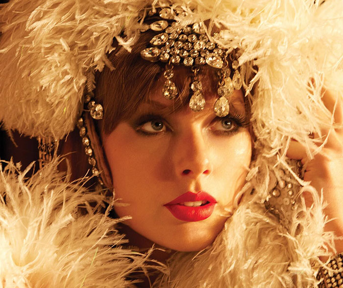 Taylor Swift wearing an ornate feathered headpiece and red lipstick, hinting a secret jab at her ex in the music video.