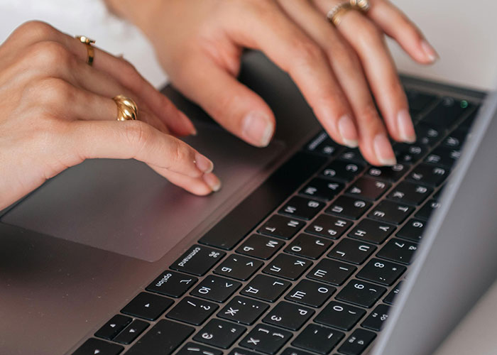 Person typing on a laptop keyboard wearing rings, illustrating loopholes used against horrible bosses in the workplace.