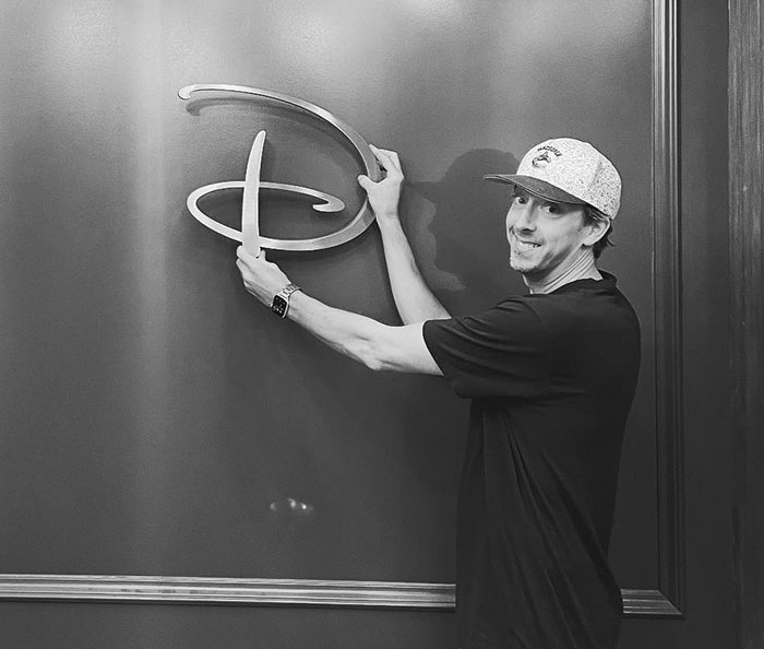 Man in a cap holding a large Disney logo on a wall, related to online backlash over breeding propaganda in new film. Man in a cap holding a large Disney logo on a wall, related to online backlash over breeding propaganda in new film.