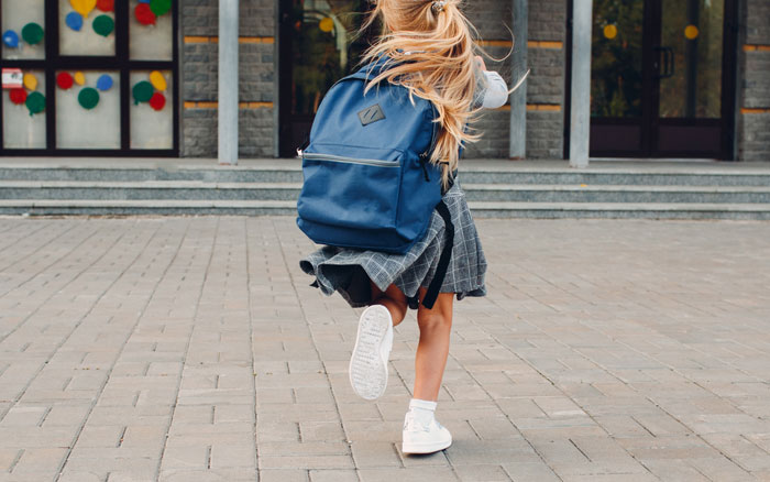 Young girl with backpack running outside a building, illustrating one-in-a-million coincidences that are hard to believe.