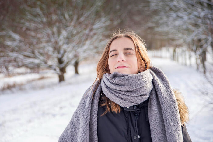 Young woman in winter coat and gray scarf outdoors, illustrating strange and dumb health hacks shared by patients.