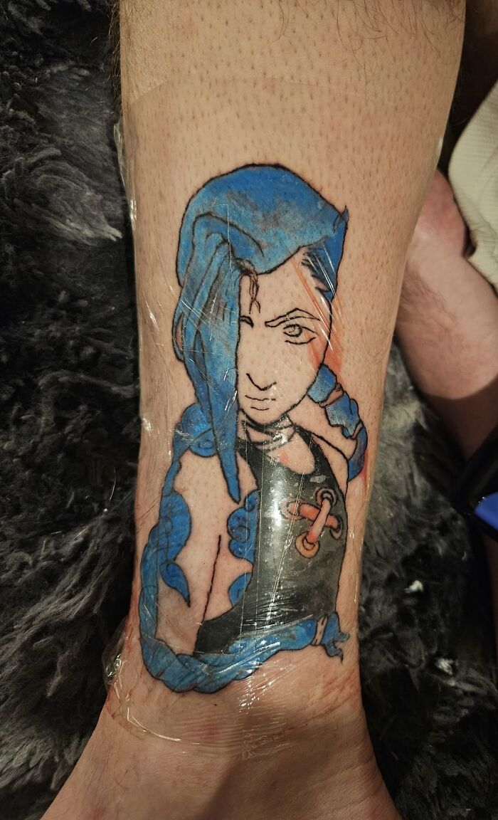 Tattoo of a stylized blue-haired female character on leg, featured in unusual tattoos people allowed on their bodies.