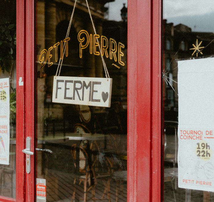 Red door with a closed sign in French hanging, showcasing a hilarious instance of being shockingly unaware of common knowledge.