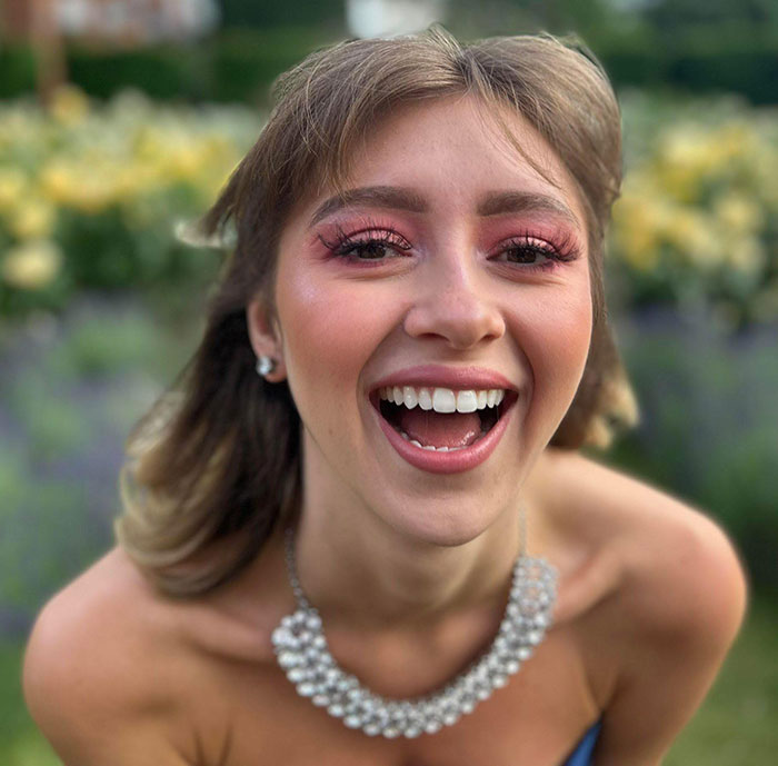 Young woman smiling outdoors wearing a pearl necklace, related to coroner exposing mom for influencing refusal of chemo. Young woman smiling outdoors wearing a pearl necklace, related to coroner exposing mom for influencing refusal of chemo.
