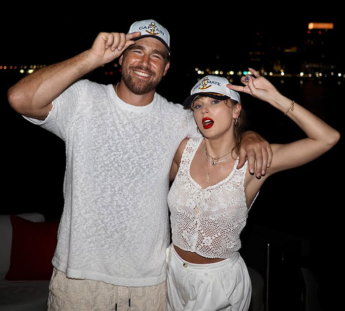 Travis Kelce and Taylor Swift wearing matching captain hats, with fans discussing Travis Kelce's manhood in new song.