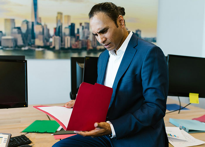 Man in blue suit reviewing documents at office desk demonstrating loopholes against horrible bosses concept.