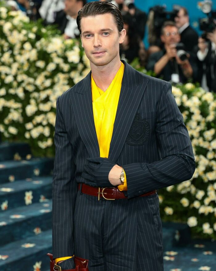 Young actor at a red carpet event wearing a pinstripe suit and yellow shirt, representing nepo babies in Hollywood.
