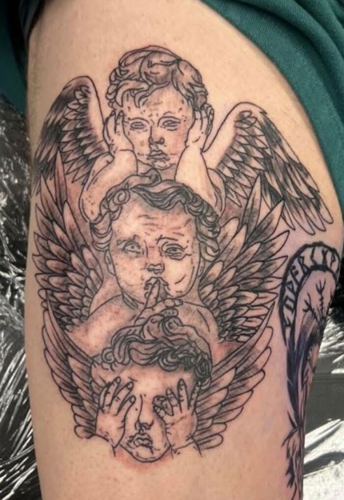 Black ink tattoo of three winged cherubs on upper arm, styled with detailed linework and shading, unusual body tattoo design.
